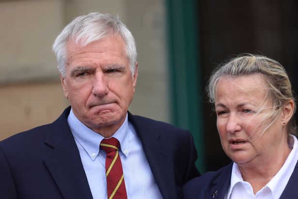 A man and woman wearing suits looking sad