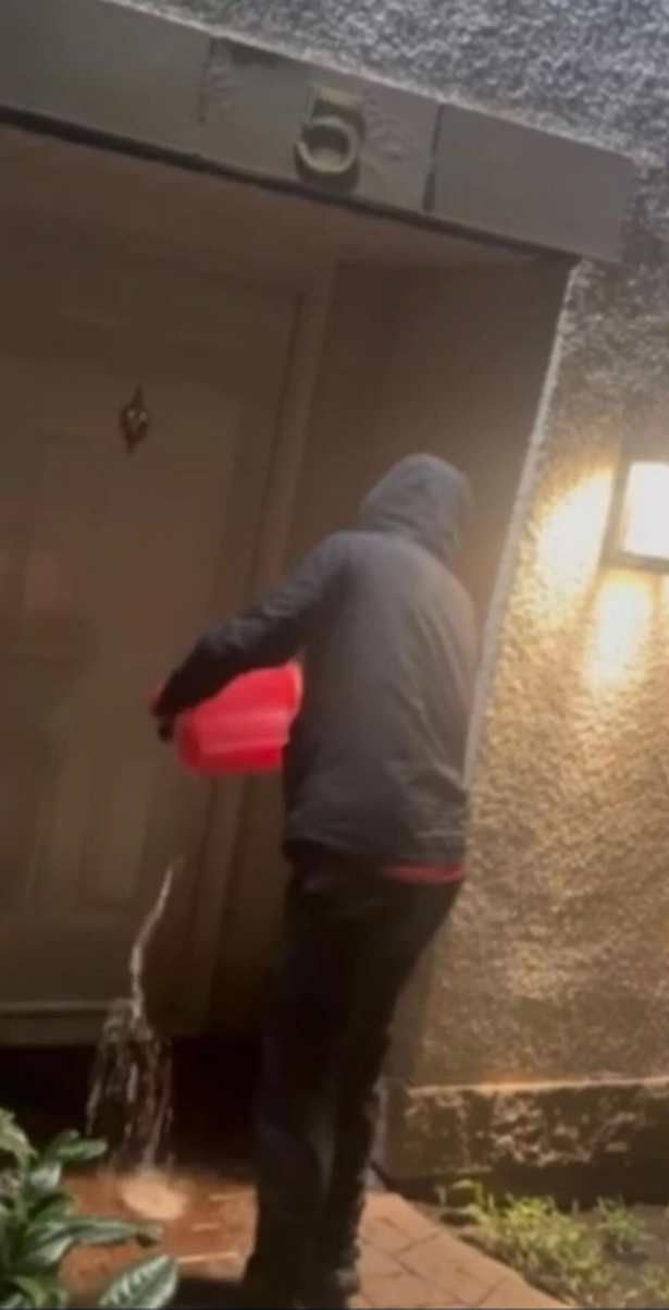 A hooded gangster setting fire to the front door of a house in Glasgow. 