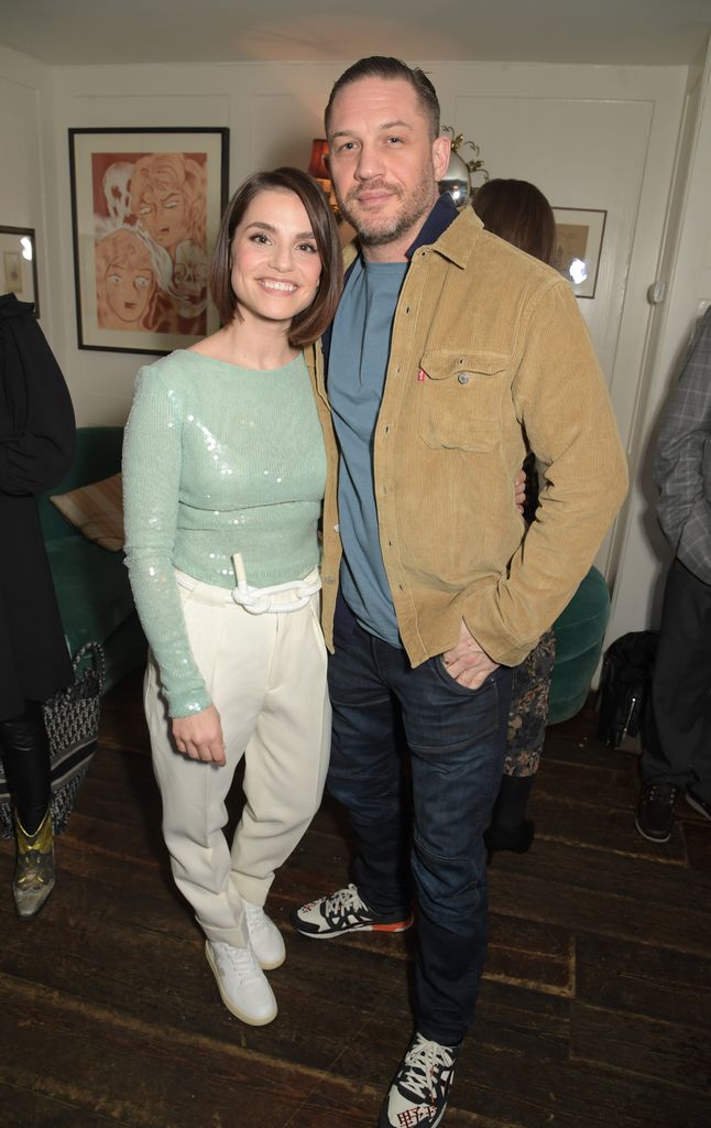 Charlotte Riley and Tom Hardy stand side by side and smile for a photo while visiting Soho House in London for an event