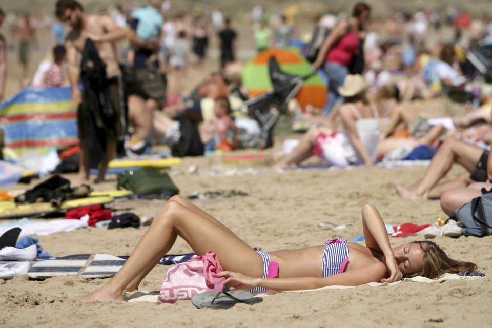 Woman sunbathing on a crowded beach.