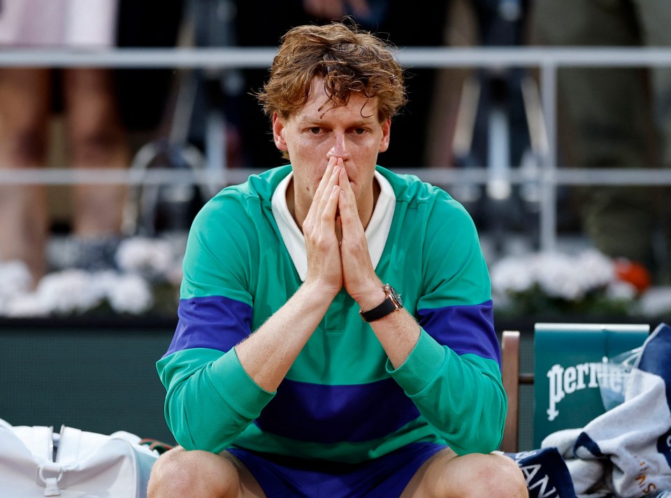 Jannik Sinner looking dejected after losing a tennis match.