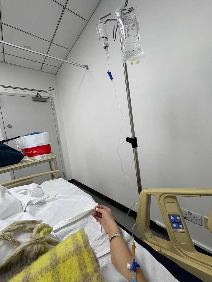 Woman in hospital bed receiving IV fluids.