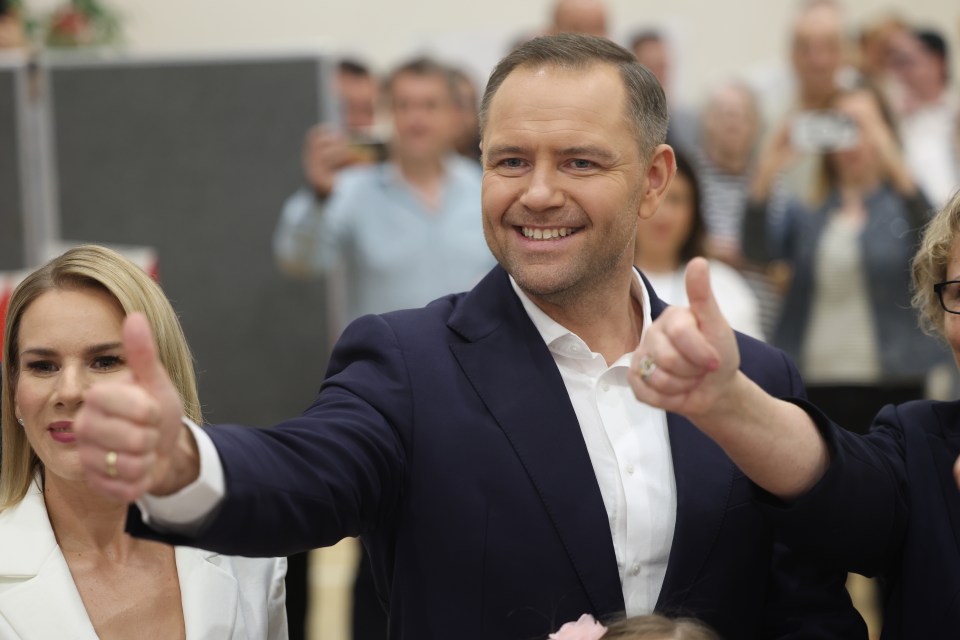 Karol Nawrocki giving a thumbs-up with his family at a Polish presidential election polling station.