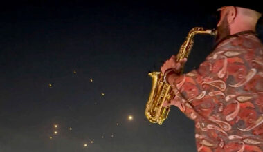 People record the missiles using their phones while a saxophonist plays the instrument, in Kfar Yassine