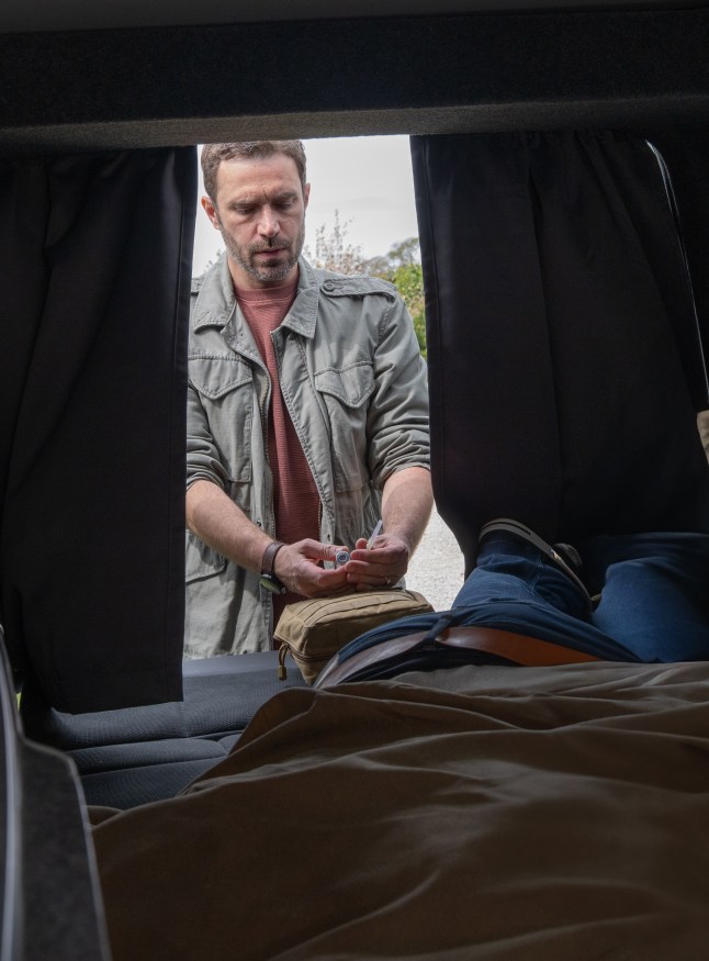 John prepares a syringe for Robert, who is laying in his van in Emmerdale