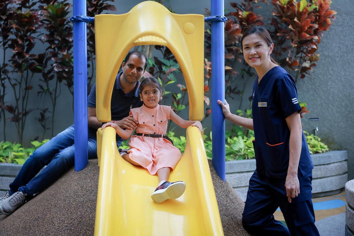 Mr Veerama Rao with his daughter Geethika Rao, 7, and her doctor Dr Chin Hui-Lin, Senior Consultant, Division of Genetics and Metabolism, Department of Paediatrics, Khoo Teck Puat - National University Children's Medical Institute, National University Hospital, at the hospital on March 29, 2025. Geethika suffers from Smith-Magenis Syndrome,