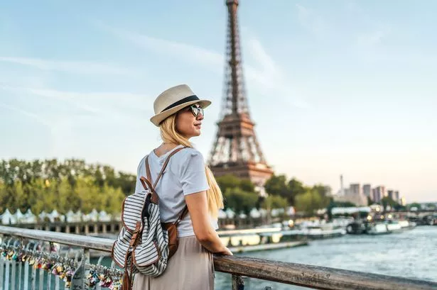 Young tourist woman enjoying in front of the Eiffel Tower and River Seine in Paris, France