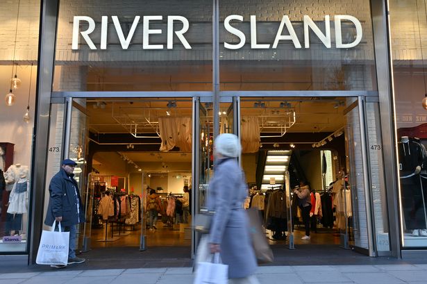 People walk past a River Island fashion retail store in Oxford Street