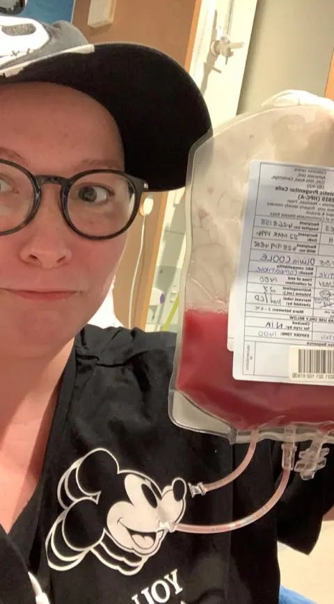 Woman in a Mickey Mouse shirt holding a bag of blood.