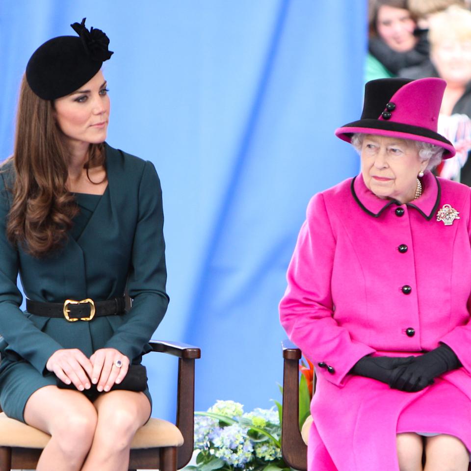  Kate Middleton wears a dark green dress with a black hat and Queen Elizabeth wears a bright pink coat. 