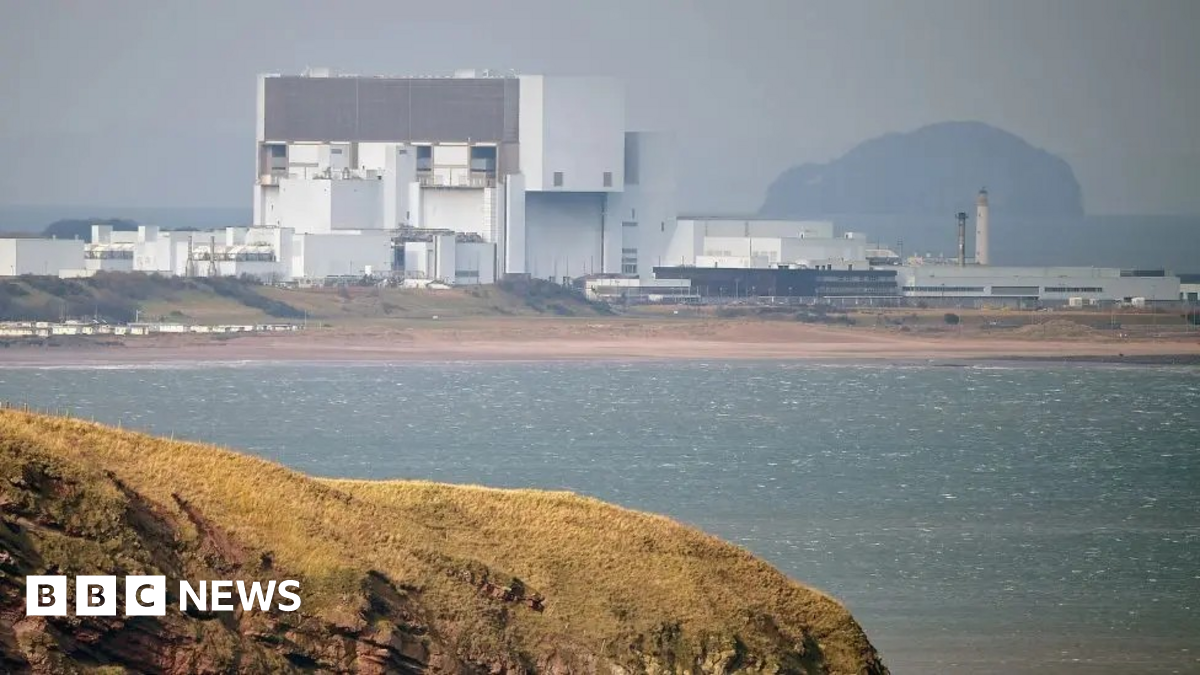 Torness nuclear power station stands in the middle distance beyond a grassy headland and the sea.