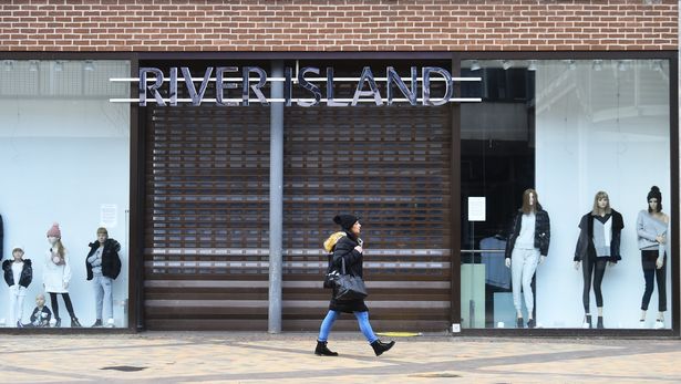 A lady walks past a closed River Island retail shop