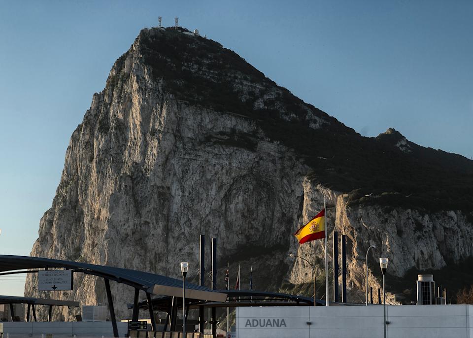 In this Wednesday, March 1, 2017 photo, a Spanish flag flies on top of the customs house on the Spanish side of the border between Spain and the British overseas territory of Gibraltar with the Rock as a background, in La Linea de la Concepcion, Southern Spain. As Gibraltar braces itself to be dragged out of the European Union along with the United Kingdom, the livelihoods of nearly 300,000 people living in an economic region spanning two countries, have been thrown up in the air. (AP Photo/Daniel Ochoa de Olza)