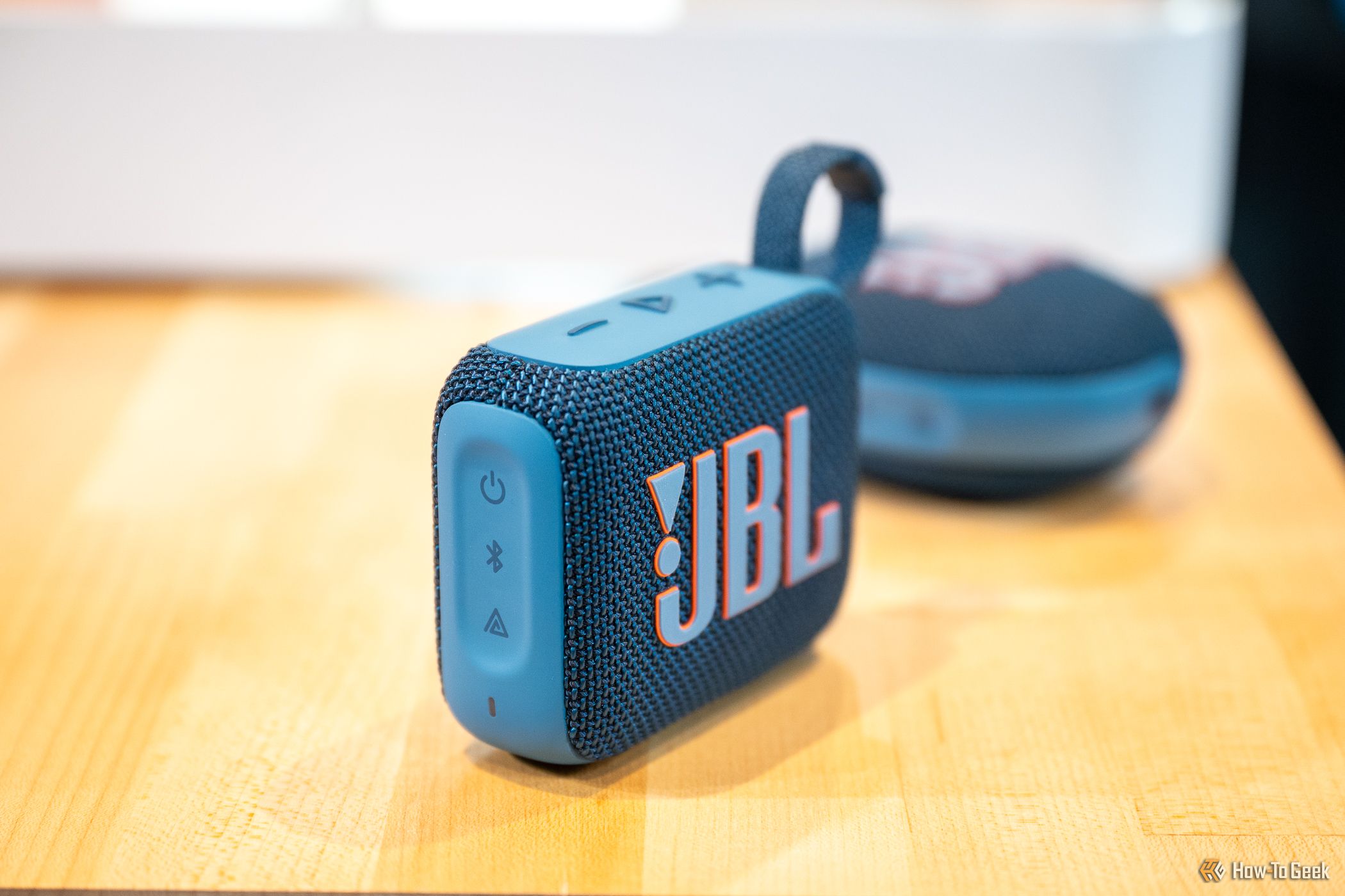 JBL Go 4 Bluetooth speaker sitting on a table in front of the JBL Clip 5.