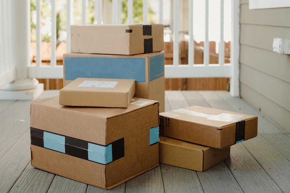 Packages are stacked on a porch, indicating a delivery