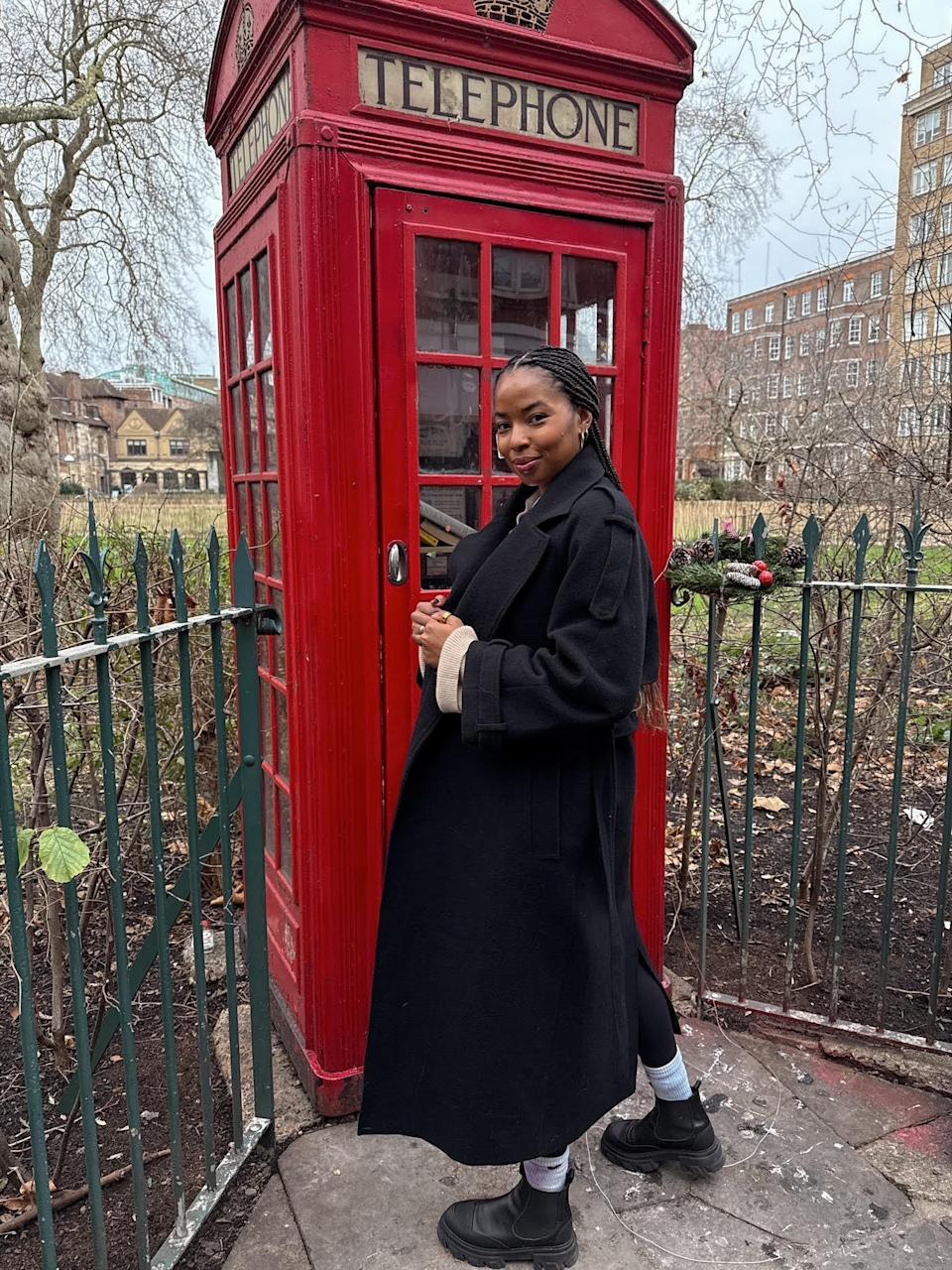 Kira West posing outside of a red London phone booth.