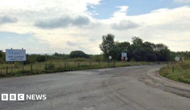 Entrance road leading to Augean at Port Clarence. There is a small white sign with the firm's name on it on the left-hand side of the road. The road is Tarmac and has a 30mph speed limit. It is surrounded by grassed areas and trees.