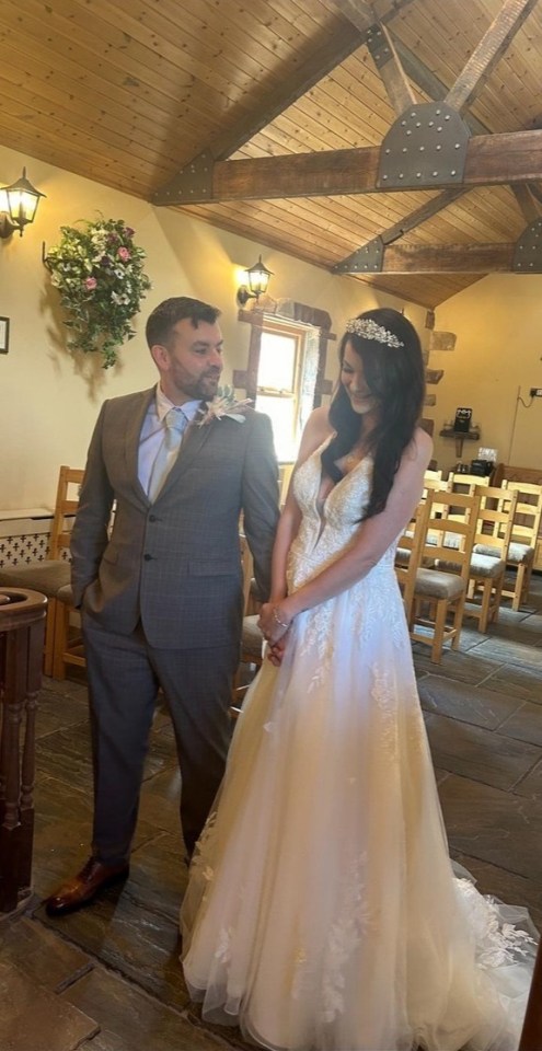 A bride and groom stand in a rustic chapel.