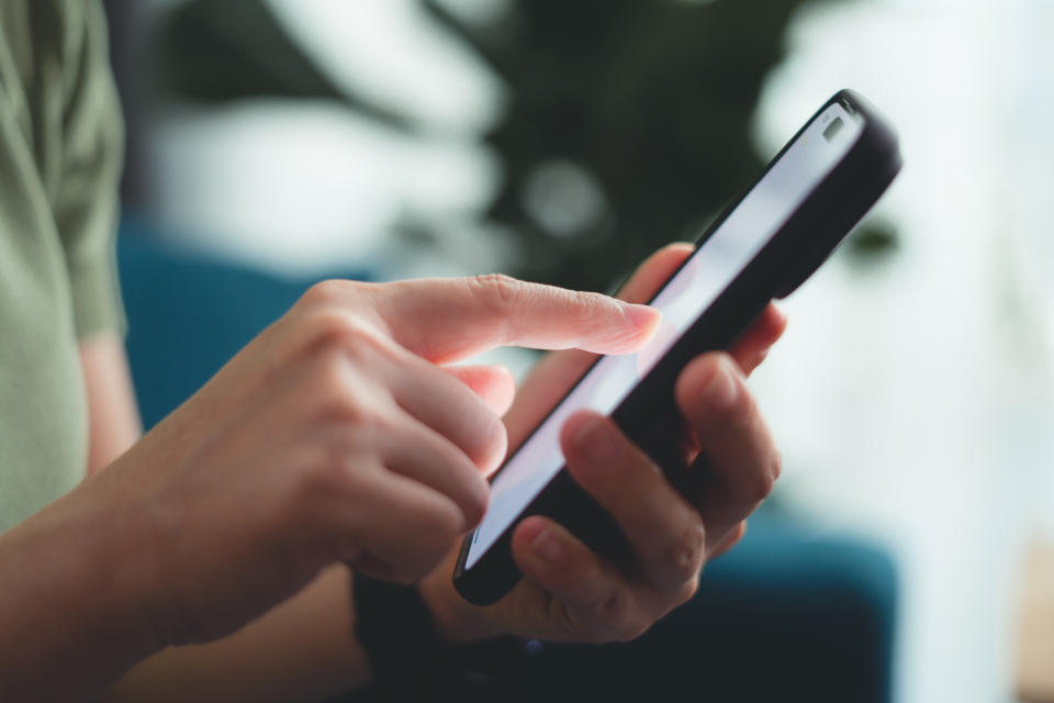A person is using a smartphone, holding it in one hand while the other hand interacts with the touchscreen