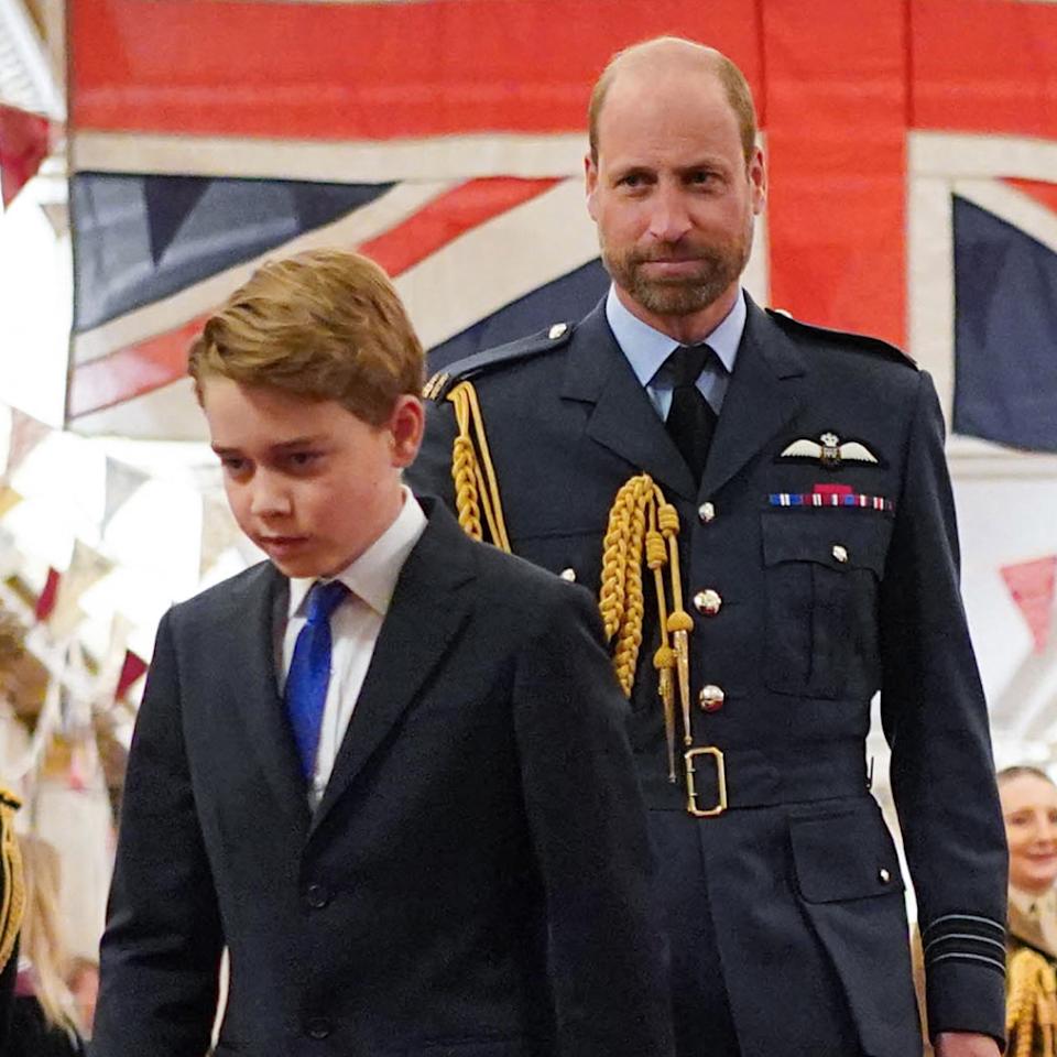  Kate Middleton looks at Prince William, who is wearing military uniform in front of the British flag, while Prince George walks with his head down. 