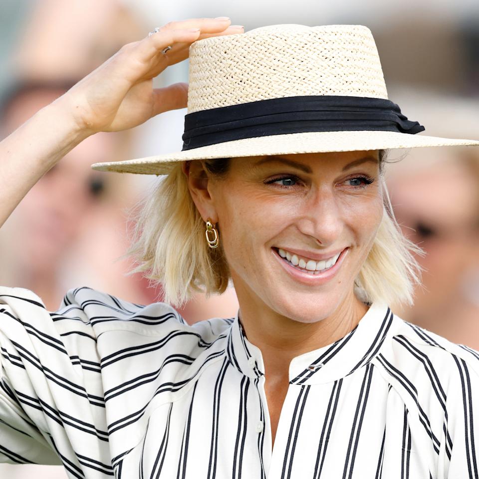  Zara Tindall in a straw hat and striped dress smiling. 