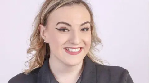 Steve James A blonde woman smiles at camera wearing a black top and she has red lipstick on.