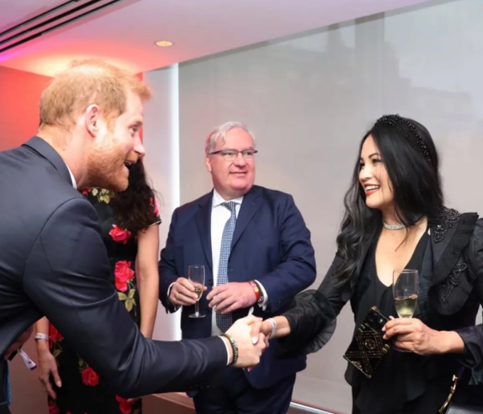 Prince Harry shaking hands with Minerva Mondejar Steiner at a charity event.