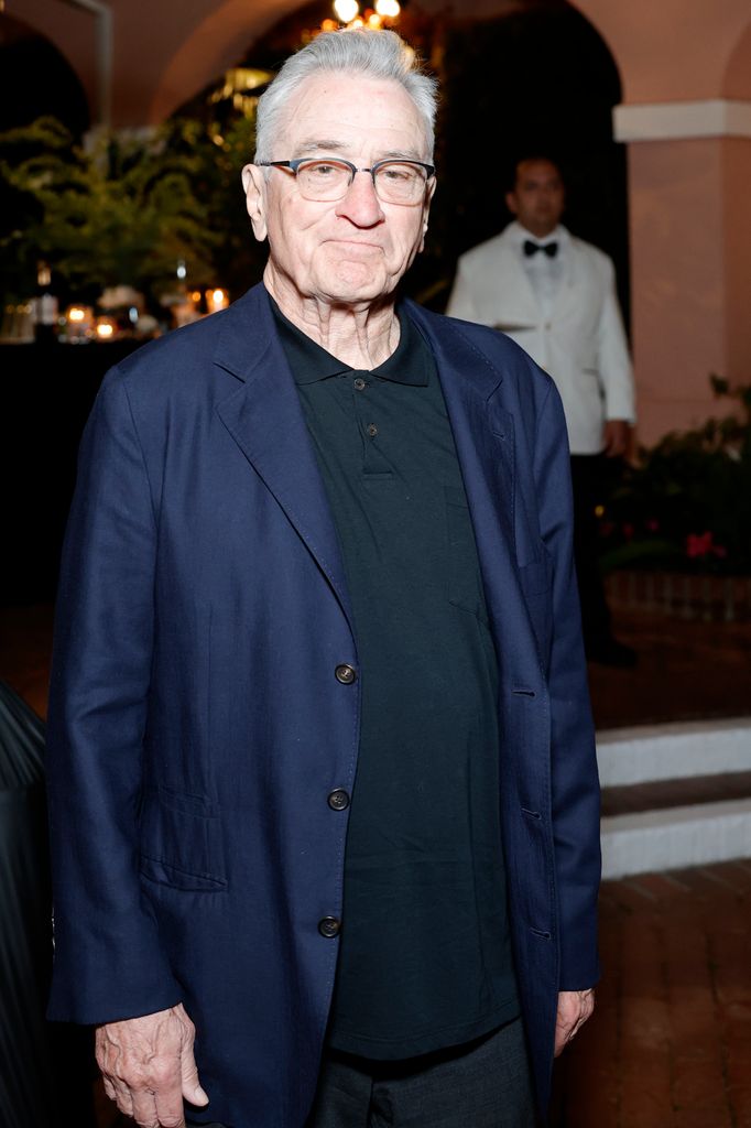 Robert De Niro in a black shirt and navy blazer