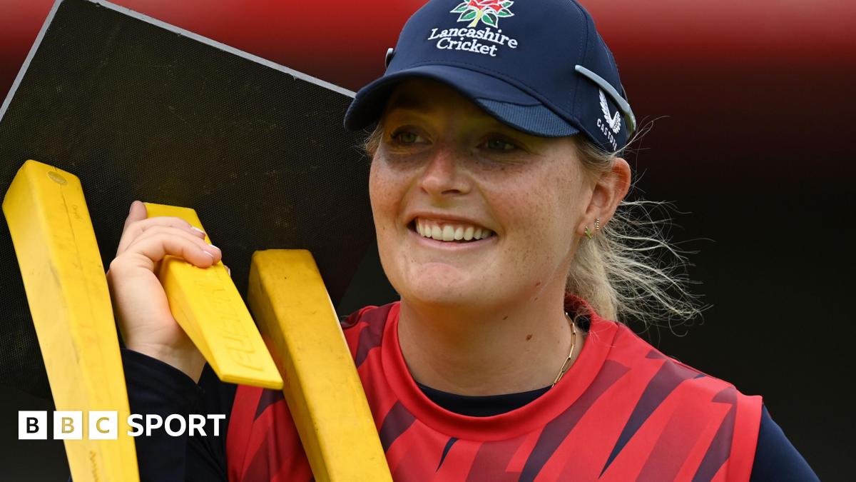 Sophie Ecclestone smiles while carrying stumps