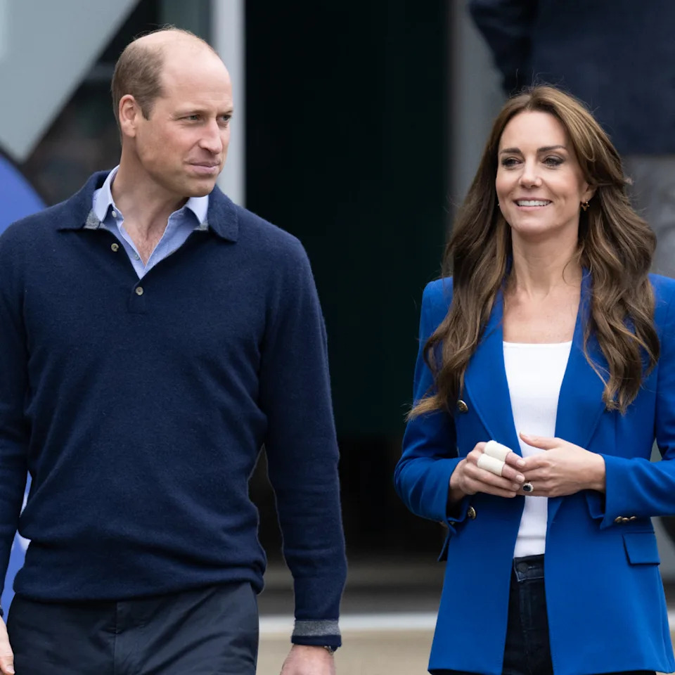  Prince William wears a blue sweater and shirt, and Kate Middleton wears a blue blazer and white T-shirt, while Princess Diana wears a blazer adorned with pearls. 