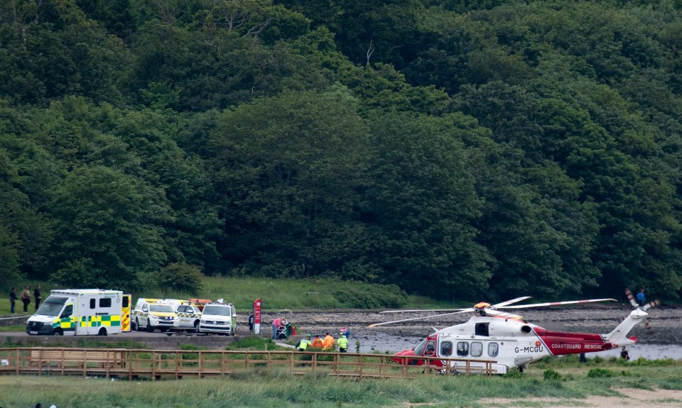 A Coastguard helicopter and emergency vehicles at a rescue scene.