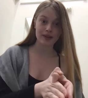 Person speaking to the camera, wearing a shawl over a top, gesturing with hands