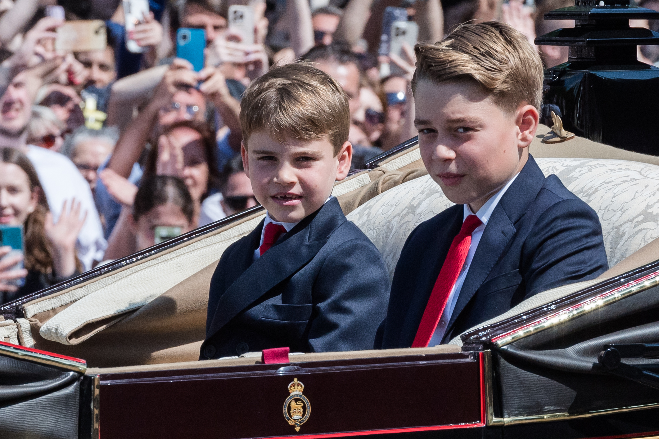 Prince George at Trooping the Colour 2025 wearing a navy suit with a white shirt and a red tie, and joining the Royal Family on the Buckingham Palace balcony