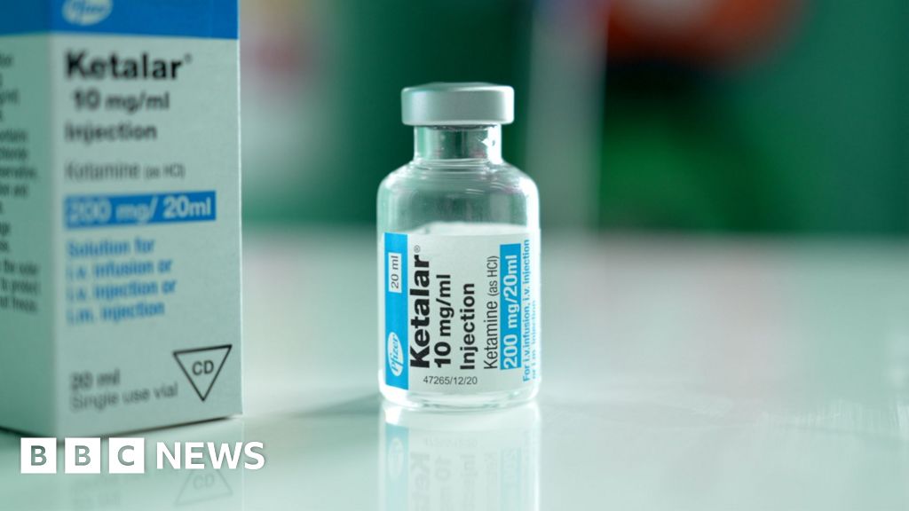 A packet and a bottle of IV ketamine on a white table
