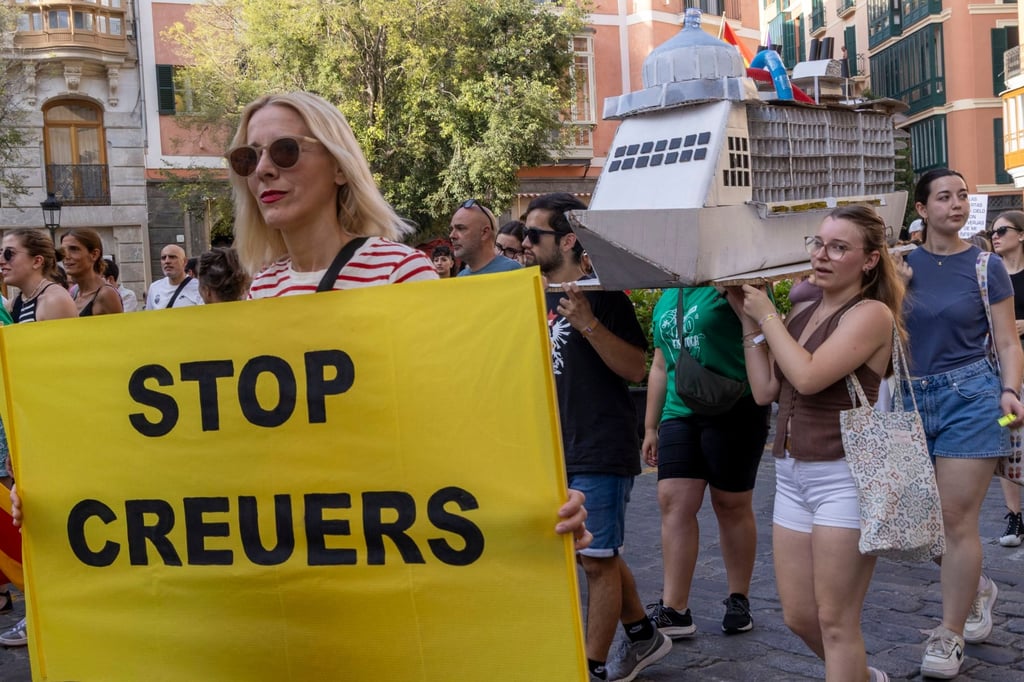 An activist holds a banner that reads “stop cruises” as part of a march to demand measures against mass tourism in Mallorca, Spain, on June 15, 2025. Photo: EPA-EFE
