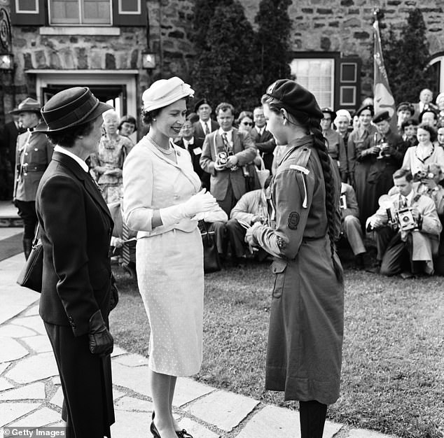 Queen Elizabeth is pictured during her visit to Canada in June 1959 presenting gold cards to the girl guide Jean Tramblay, aged 15, in Saguenay, Quebec
