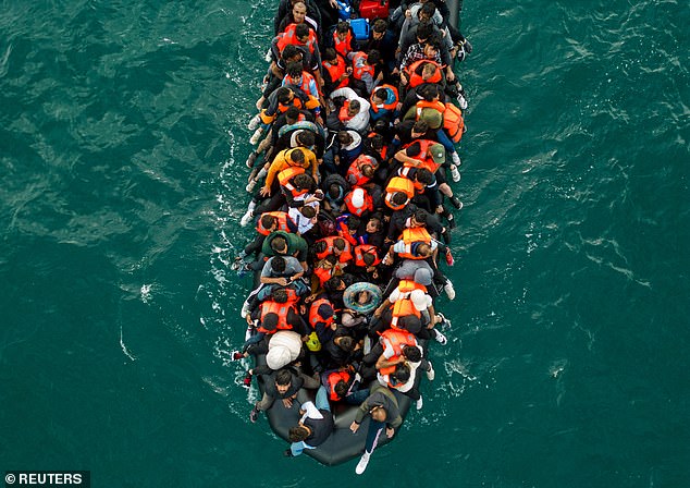 An inflatable dinghy pictured carrying migrants makes its way towards the UK