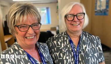Two GP receptionists Jayne Bond and Sandra Brewster smiling ahead of their daily pressured stint answering the telephones first thing in the morning  from patients trying to get an appointment from the surgery.