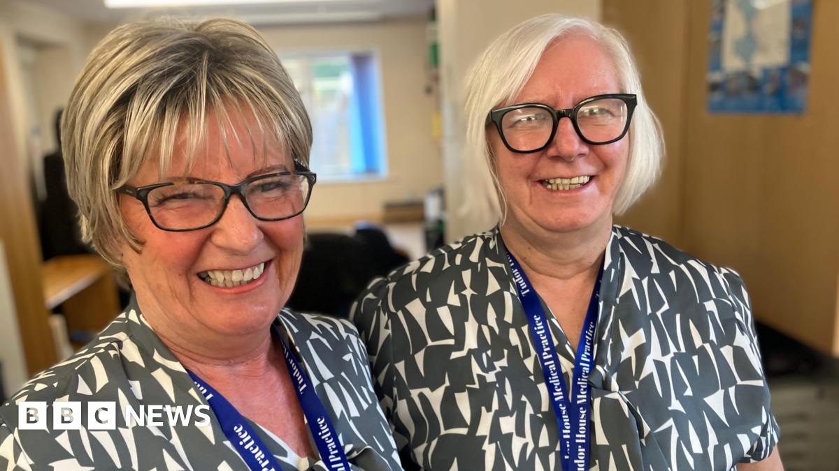 Two GP receptionists Jayne Bond and Sandra Brewster smiling ahead of their daily pressured stint answering the telephones first thing in the morning  from patients trying to get an appointment from the surgery.