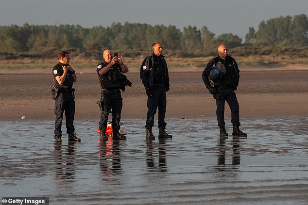 French police watch as migrants board dinghies on May 31, 2025 in Gravelines, France