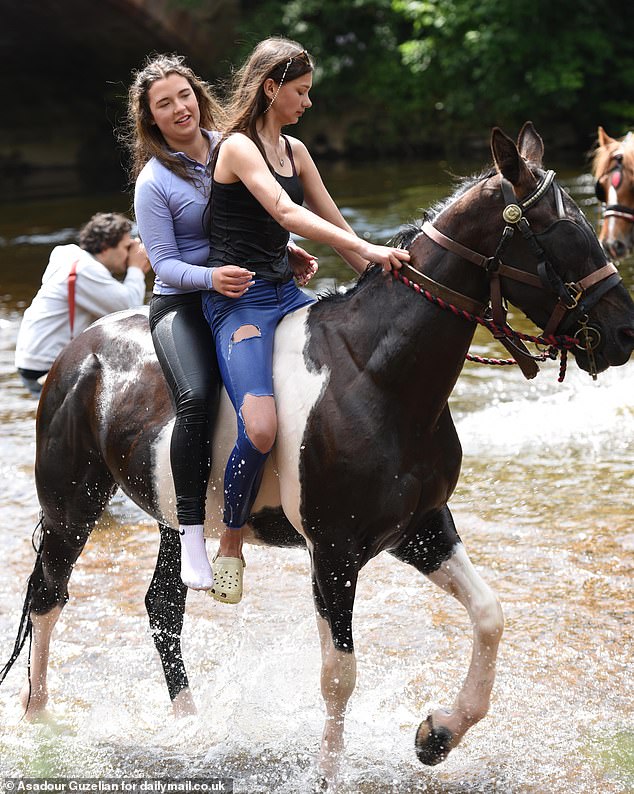Two women take a horse for a dip in the River Eden on the second day of the Appleby Horse Fair
