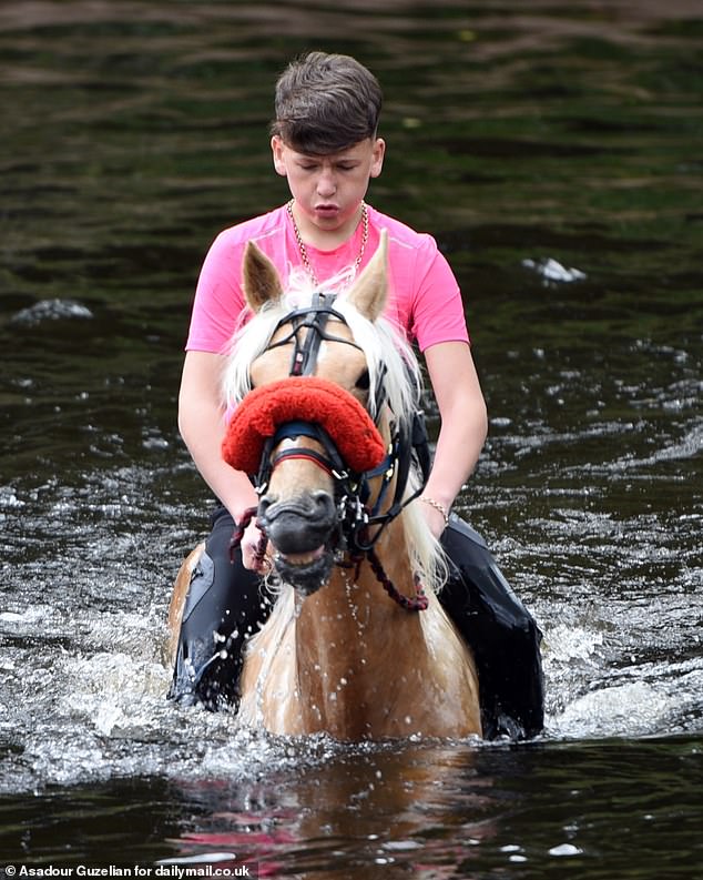 A boy takes a horse for a dip in the River Eden on the second day of the Appleby Horse Fair