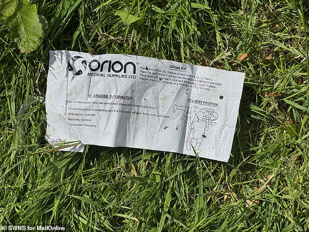 The grass is littered with slips providing emergency information for overdoses