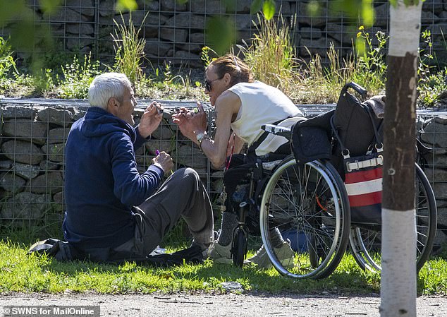 The couple are middle aged, skinny with cheekbones and dirty fingernails exposed as they suck on their pipes