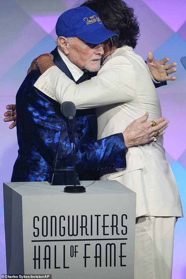 Accepting his honour on stage, he admitted: 'I do feel his presence' (pictured with John)