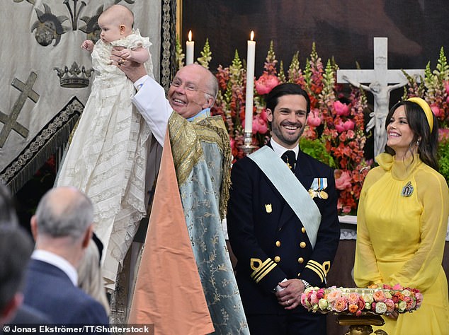 The chief priest, Bishop Johan Dalman, holds up Princess Ines after he baptizes her