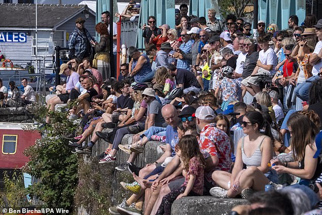 Sunbathers pictured sitting on a wall at Bristol Harbourside on Sunday. Parts of the UK will bask in 24C heat today as the balmy summer conditions continue