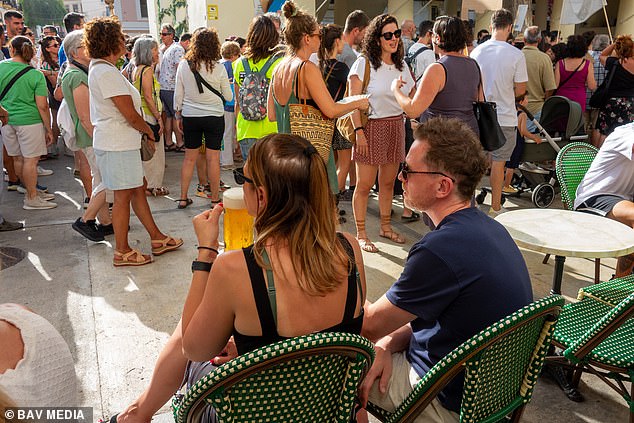 Tourists seen still consuming their meals and drinks as the anti-tourism protesters go by in the Old Town in Ibiza on June 15 2025