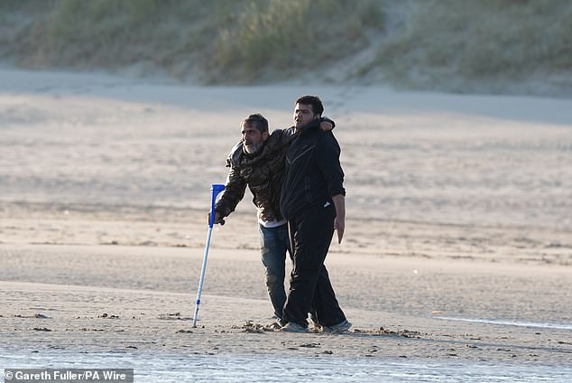 A bearded middle-aged man, who could only hobble towards the waves aided by a friend