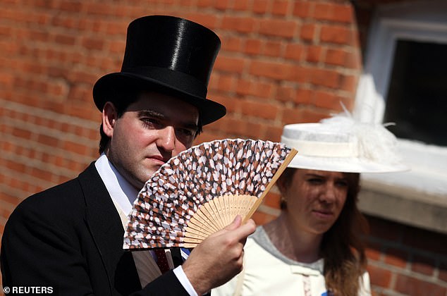 This racegoer keeps cool in the heat with a handy fan when attending Royal Ascot
